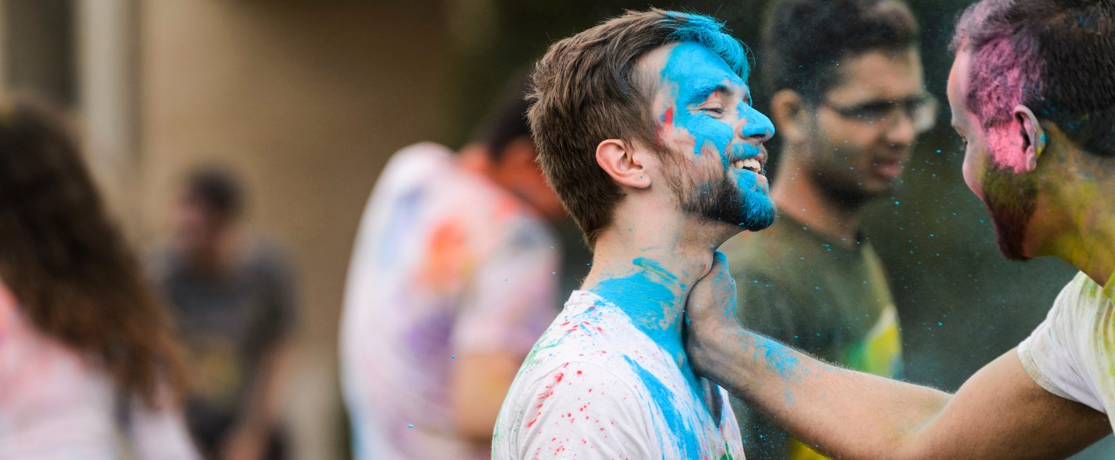 male student with blue chalked face smiles during the festival of colors, an Indian tradition.
